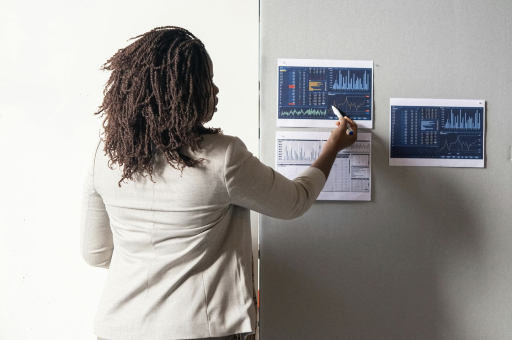 A person looking at printed charts on a board, pointing to information on them.
